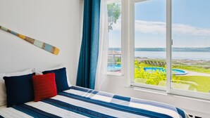 Un dormitorio con un ventanal que ofrece vistas a una piscina y zonas verdes.