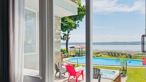 Vista de un patio trasero con piscina, mobiliario exterior y una vista panorámica de un lago.