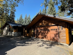 Set amidst the woods, this cabin-style building features a garage with a large door and multiple windows.