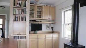 Una cocina con armarios de madera, una estufa negra y un ventanal.