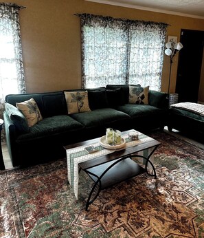 A living room with a sofa, a coffee table, and a patterned rug.