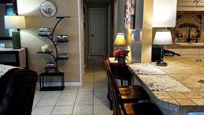 A kitchen with a tiled floor, wooden bar stools, a dining table, and a kitchen counter. - Downtown OS.  Quite & Walkable.  2 Sm Pets. Refurbished.  GolfCart
Rental  (Ocean Springs)