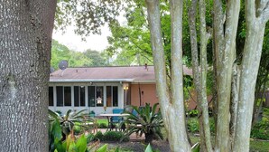 A house with a porch, surrounded by lush greenery and trees. - Downtown OS.  Quite & Walkable.  2 Sm Pets. Refurbished.  GolfCart
Rental  (Ocean Springs)