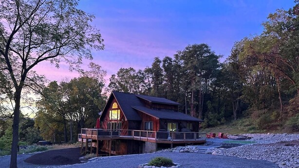 Een houten chalet met terras, omgeven door grind en bomen.