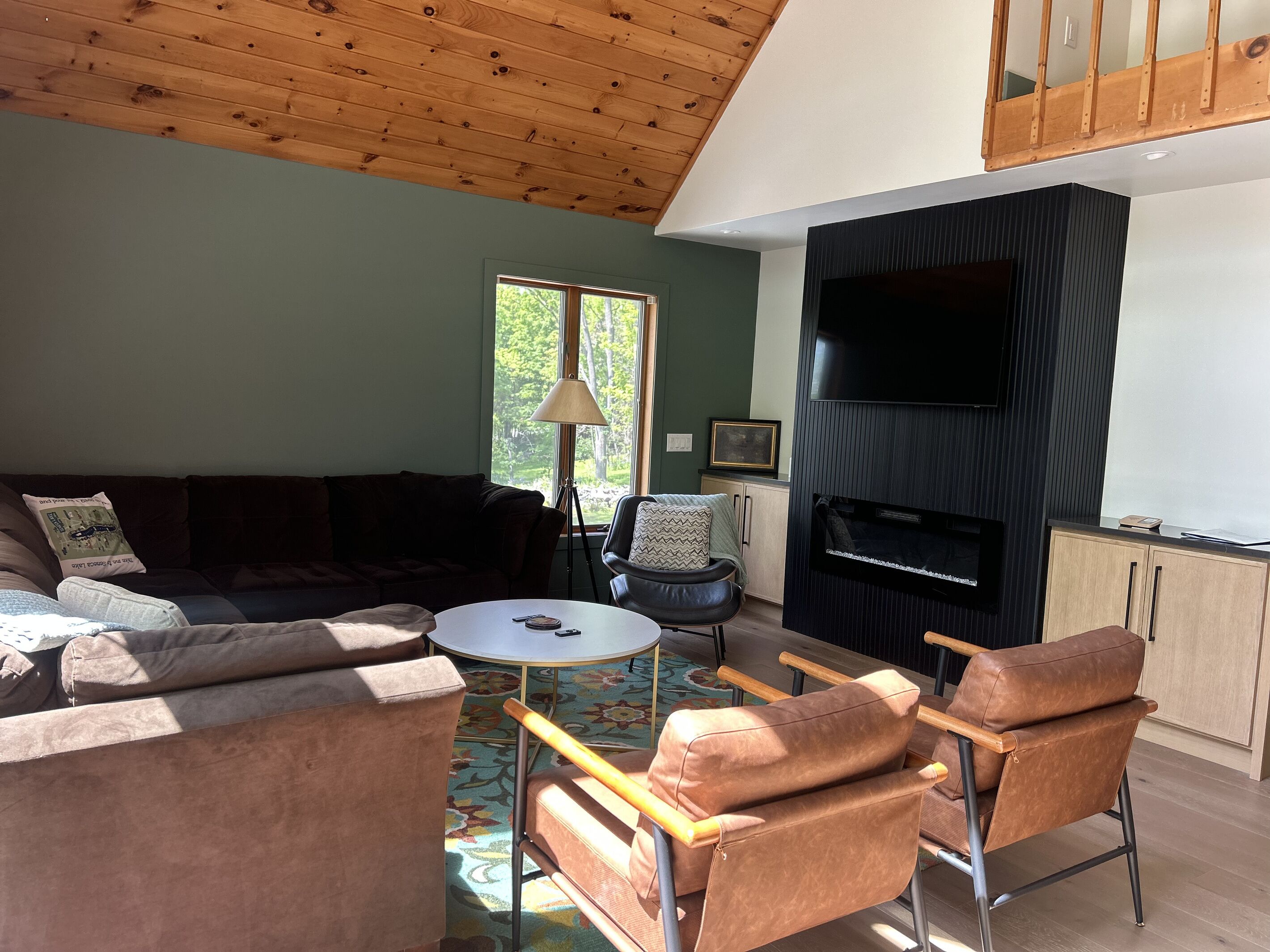 A living room with a sectional sofa, a coffee table, a fireplace, and a television.