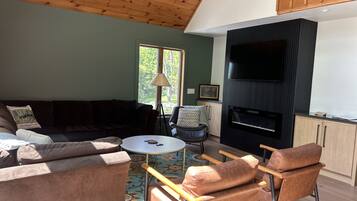 A living room with a sectional sofa, a coffee table, a fireplace, and a television.