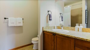 A bathroom with a wooden vanity, a sink, and a mirror. There are two towels hanging on the wall.