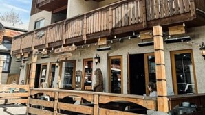 A wooden building with balconies and multiple windows.