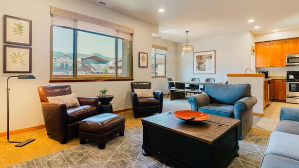 A modern living room with leather sofas, a coffee table, and a dining area with a table and chairs.
