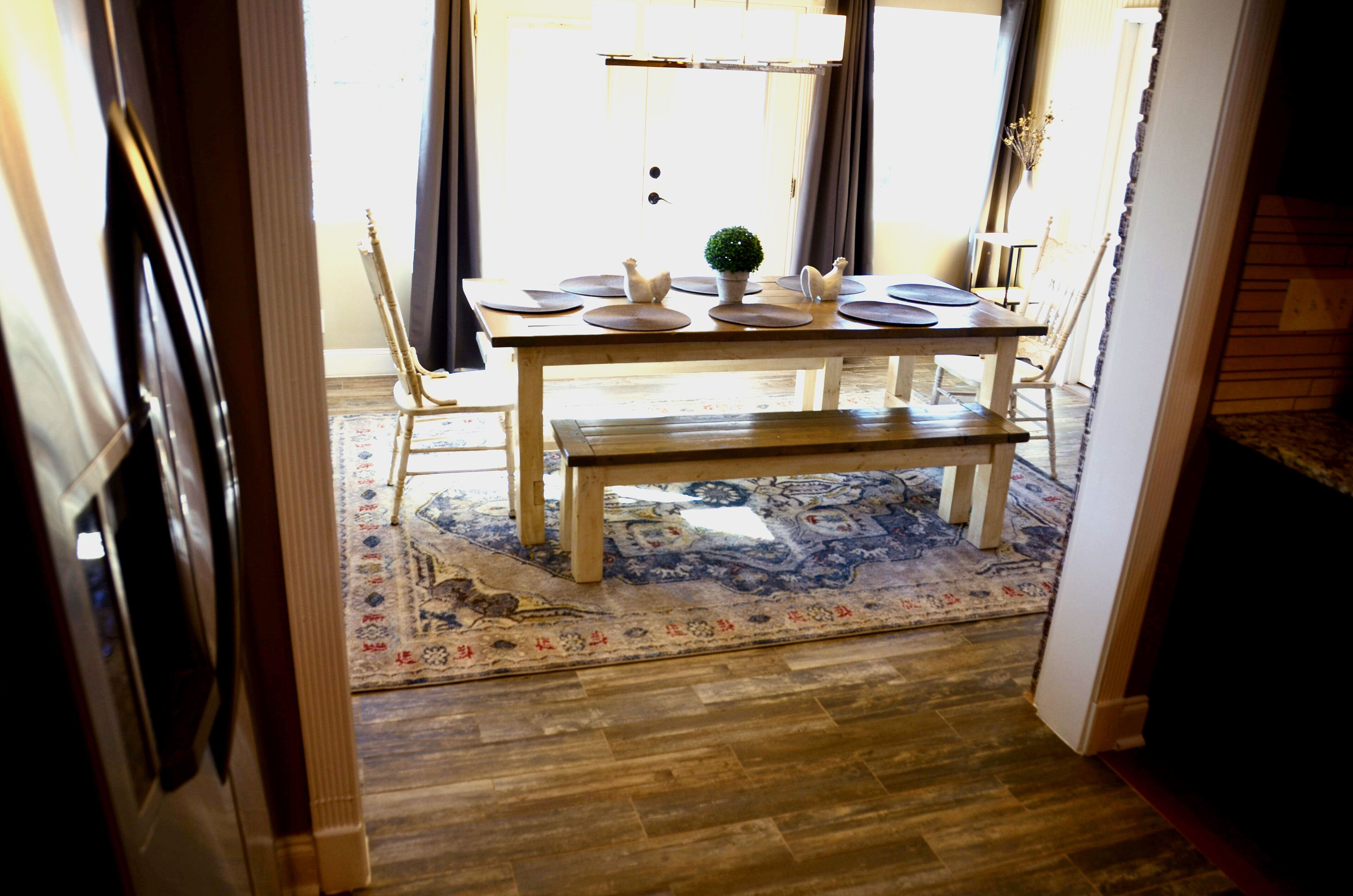 Un comedor con una mesa de madera, sillas, un banco y una alfombra.