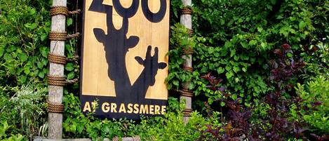 A wooden sign for the Nashville Zoo, featuring a giraffe silhouette and the text "Nashville Zoo at Grassmere."