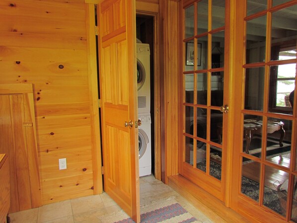 A wooden door leading to a laundry area with a washing machine. - Driftwood Cottage; cozy oceanfront, 2 Kayaks, Wood Stove, Porch, Sunsets. (Brooksville)