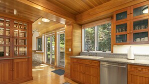 A kitchen with wooden cabinets, a stainless steel dishwasher, and a window providing natural light. - Discover an Architectural Gem West (Vail)