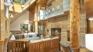 A cozy cabin interior with a stone fireplace, wooden furniture, and a balcony with a railing. - Discover an Architectural Gem West (Vail)