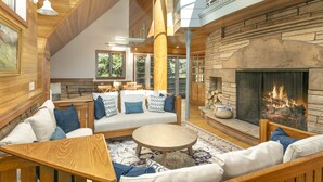A cozy interior with a stone fireplace, wooden furniture, and a high ceiling with exposed beams. - Discover an Architectural Gem West (Vail)