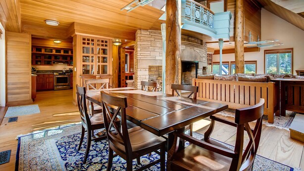 A spacious dining area with a long wooden table and chairs, a kitchen in the background, and a loft with a balcony. - Discover an Architectural Gem West (Vail)