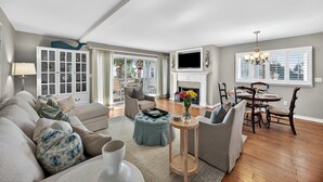 Un salon spacieux comprenant un canapé, un pouf et un coin repas avec des chaises et une table.