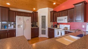 A kitchen with wooden cabinets, granite countertops, a white refrigerator, a microwave, and a sink. - Single Level w/ Hot Tub and patios with 360° Views! (Westcliffe)