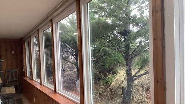 A room with a long wooden bench along a wall with large windows overlooking a forest. - 3 Br Cottage right on beach - Beautiful view of beach/water - Pets welcome! (Prime Hook Beach)