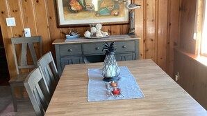 A dining area with a wooden table, chairs, and a decorative centerpiece. - 3 Br Cottage right on beach - Beautiful view of beach/water - Pets welcome! (Prime Hook Beach)