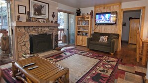 Una sala de estar acogedora con chimenea, televisor, estantería y un sofá cómodo.