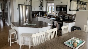 A modern kitchen with white cabinetry, stainless steel appliances, and a central island with bar stools.