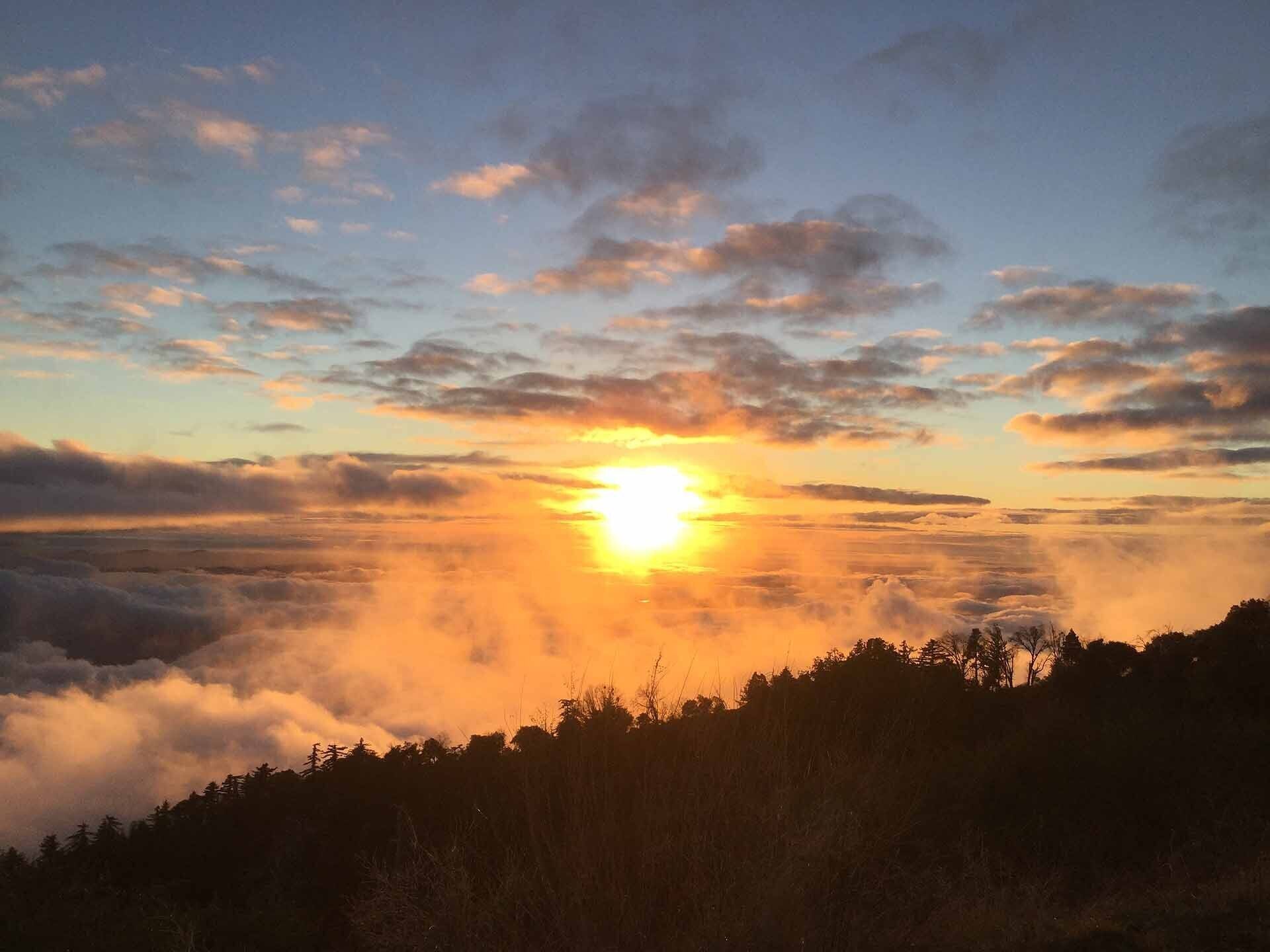 Un lever de soleil sur une chaîne de montagnes boisée.