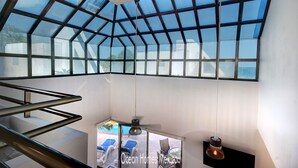 A modern interior with a glass ceiling, a staircase, and a pool area. - Oceanfront Luxury Home Wifi 4 Smart TV'S Pool & Spa  (Puerto Morelos)
