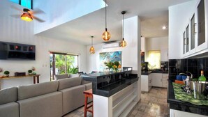 A modern kitchen with a central island, pendant lighting, and a built-in oven. - Oceanfront Luxury Home Wifi 4 Smart TV'S Pool & Spa  (Puerto Morelos)