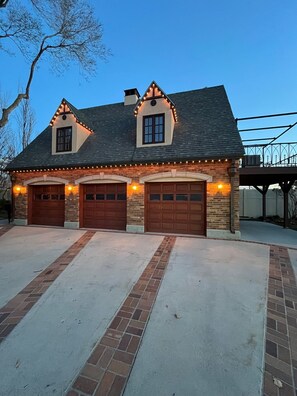 A two-story house with a brick facade, two garage doors, and a sloped roof.