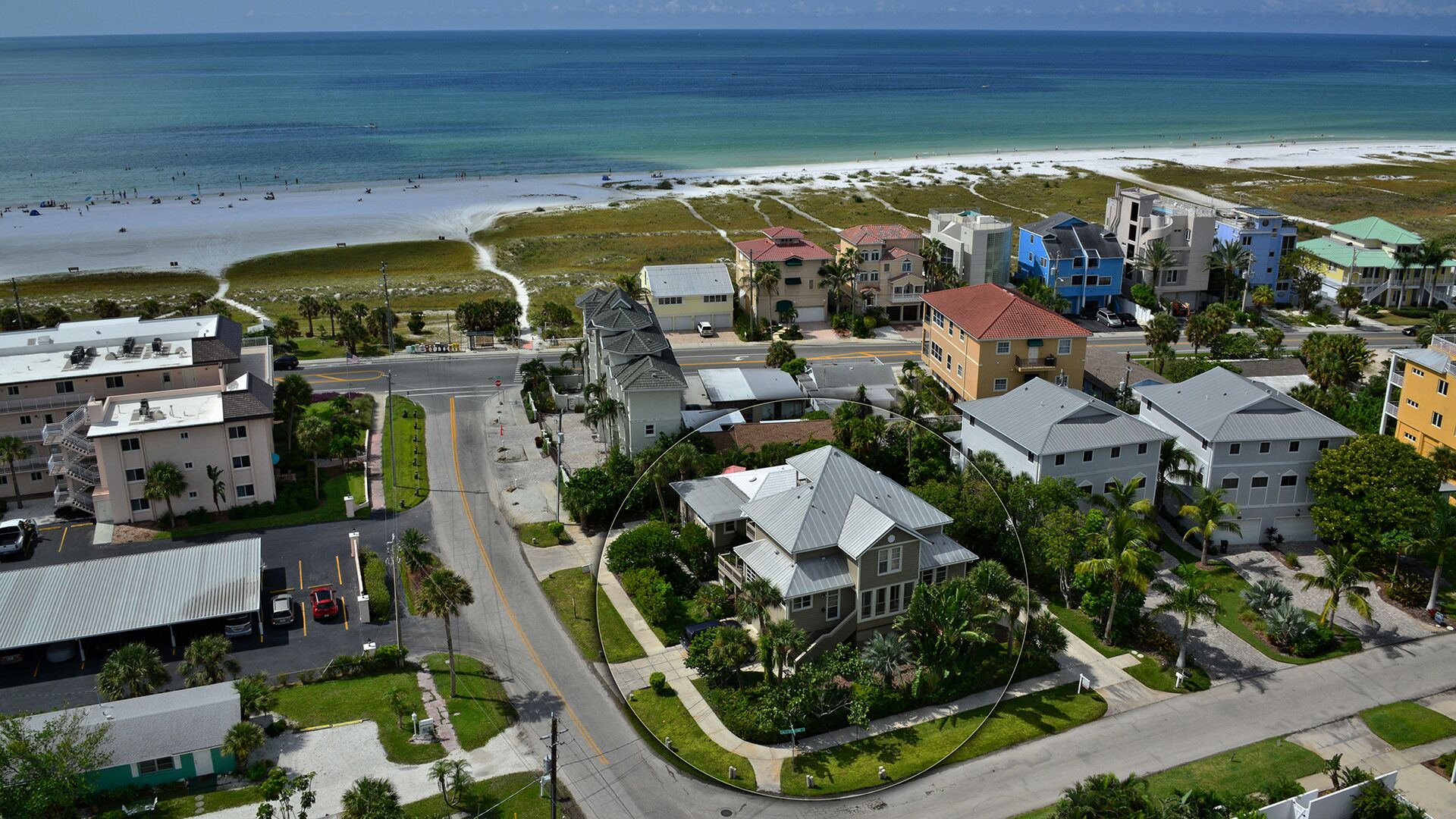 A coastal town with a beach, residential buildings, and a road.
