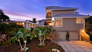 A modern two-story house with a balcony, surrounded by landscaped gardens and palm trees. -  🌷 Stunning 1-Bedroom Apartment Overlooking Pool, steps to Siesta Beach (Siesta Key)