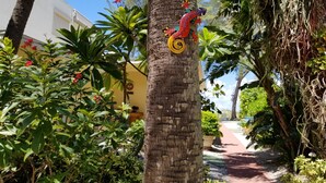 A garden with a variety of plants and a decorative sculpture on a tree. - Beachfront Cottages GULF at Beautiful Sandy Shores on Gulf of America (Indian Rocks Beach)