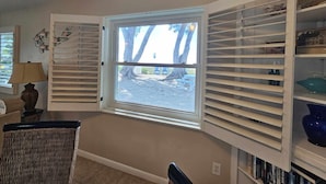 A room with a large window, a bookshelf, and a lamp. - Beachfront Cottages GULF at Beautiful Sandy Shores on Gulf of America (Indian Rocks Beach)