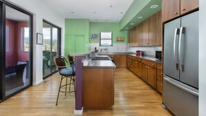 Een moderne keuken met houten kastjes, een roestvrijstalen koelkast en een centraal eiland met barkrukken.