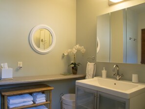 A bathroom with a sink, mirror, and a shelf with towels.
