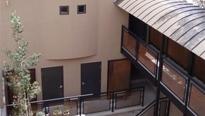 Un bâtiment doté d’un balcon incurvé, d’un petit espace extérieur aménagé en coin salon et d’un escalier menant à un étage supérieur.