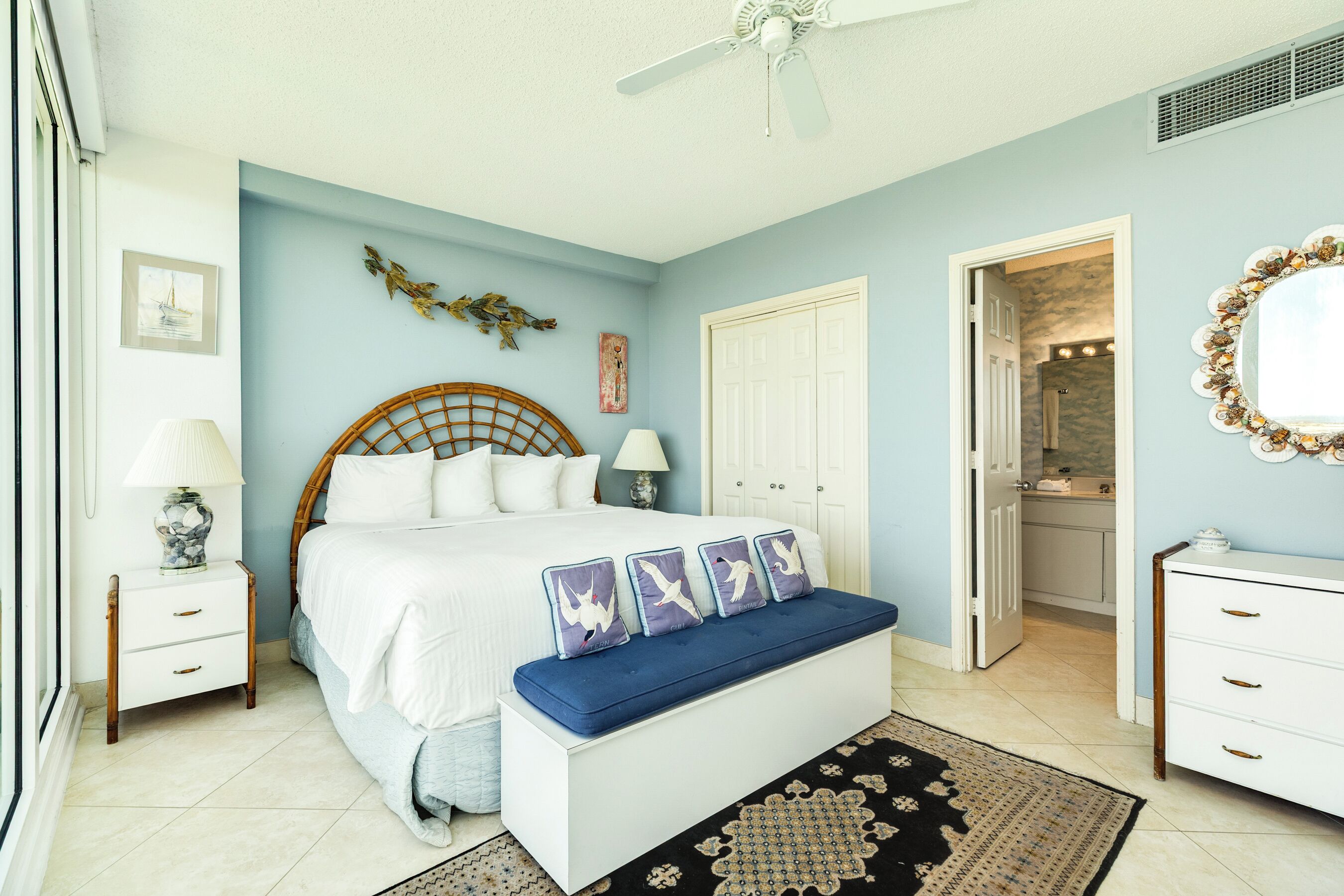 A bedroom with a bed, bedside tables, a bench, a dresser, and a mirror.