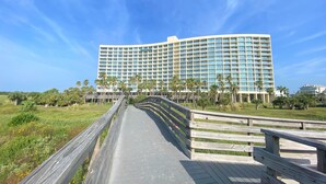 A large hotel with a modern design, featuring a long pathway leading to the entrance. -   Three bed room, beach- front  end unit with magnificent views, on the11 floor. (Galveston)