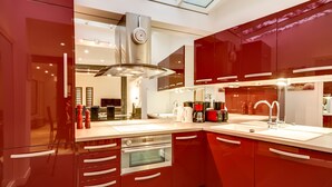 Una cocina moderna con gabinetes rojos, electrodomésticos de acero inoxidable y un tragaluz.