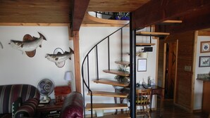 Un salón acogedor con una escalera espiral, muebles de madera y ciervos y peces montados en la pared.