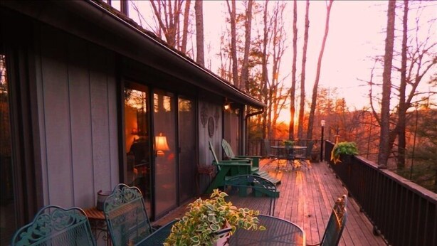 A wooden deck with outdoor seating, a table, and chairs.