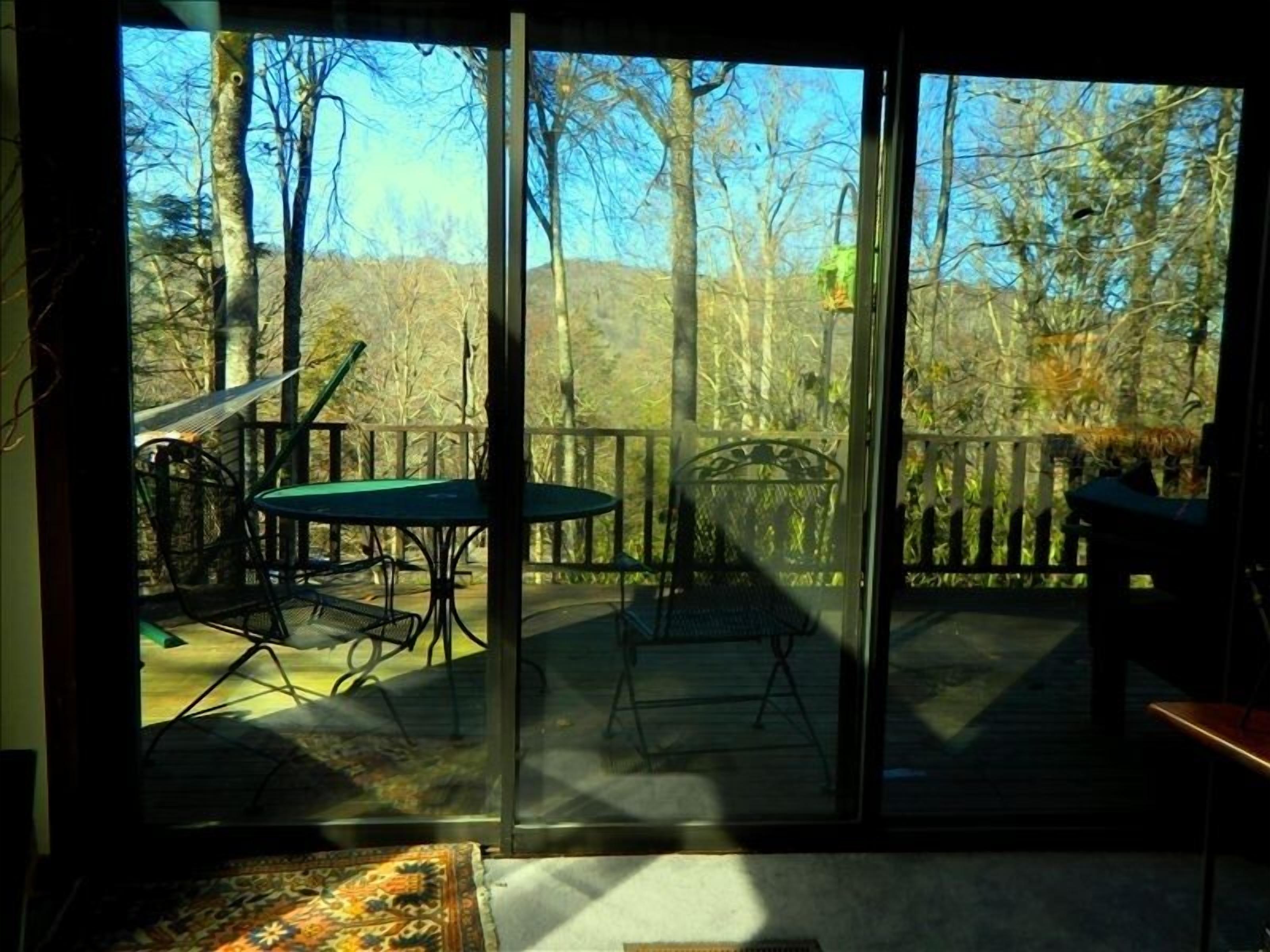 A room with a sliding glass door leading to an outdoor deck with a table and chairs.