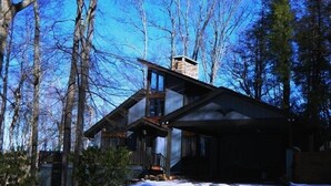 A cabin with a stone chimney, wooden exterior, and a porch.