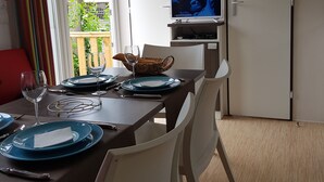 Un coin repas avec une table dressée pour deux personnes, un téléviseur fixé au mur et une porte portant l’inscription « Salle de bain ».