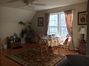 A dining area with a table set for two, a ceiling fan, a potted plant, and a window with curtains. - SPRING INTO SAVINGS Large Tranquil, Private Suite By The Sea, Birders Paradise (Little Compton)