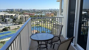 Ein Balkon mit Tisch und Stühlen mit Blick auf einen Pool und die Stadtlandschaft.