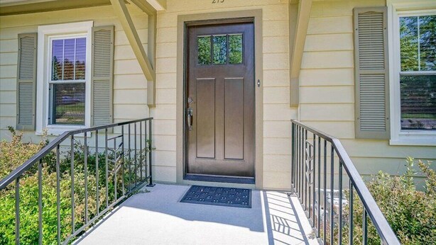 A house with a brown front door, number 213, and a small porch with a metal railing. - A Pleasant Retreat (Sun Prairie)