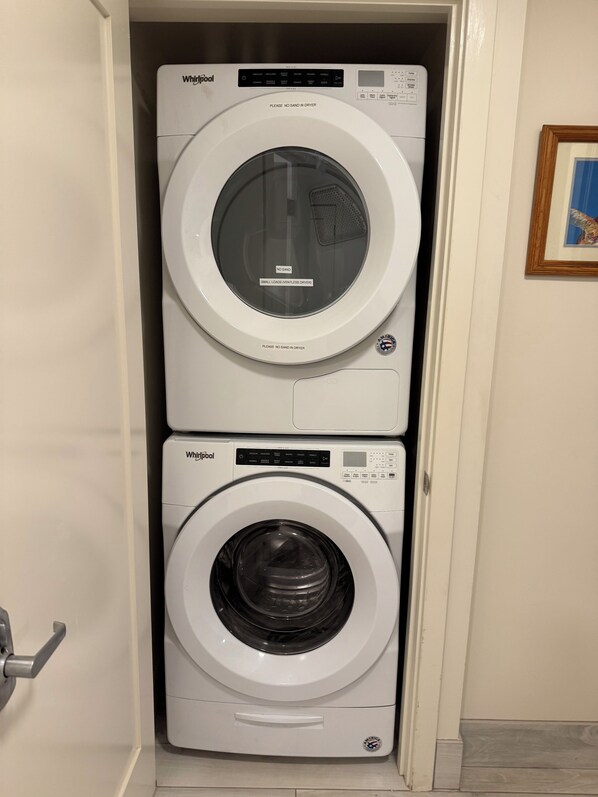 Une petite buanderie à deux portes, équipée d’un lave-linge et d’un sèche-linge de la marque Whirlpool.
