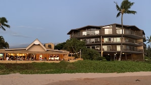 Un hôtel situé en bord de mer, doté de nombreux balcons, d’un restaurant et de palmiers.